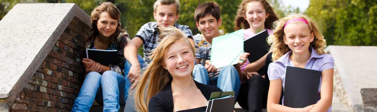 Teen and pre-teen students on the steps outside of school