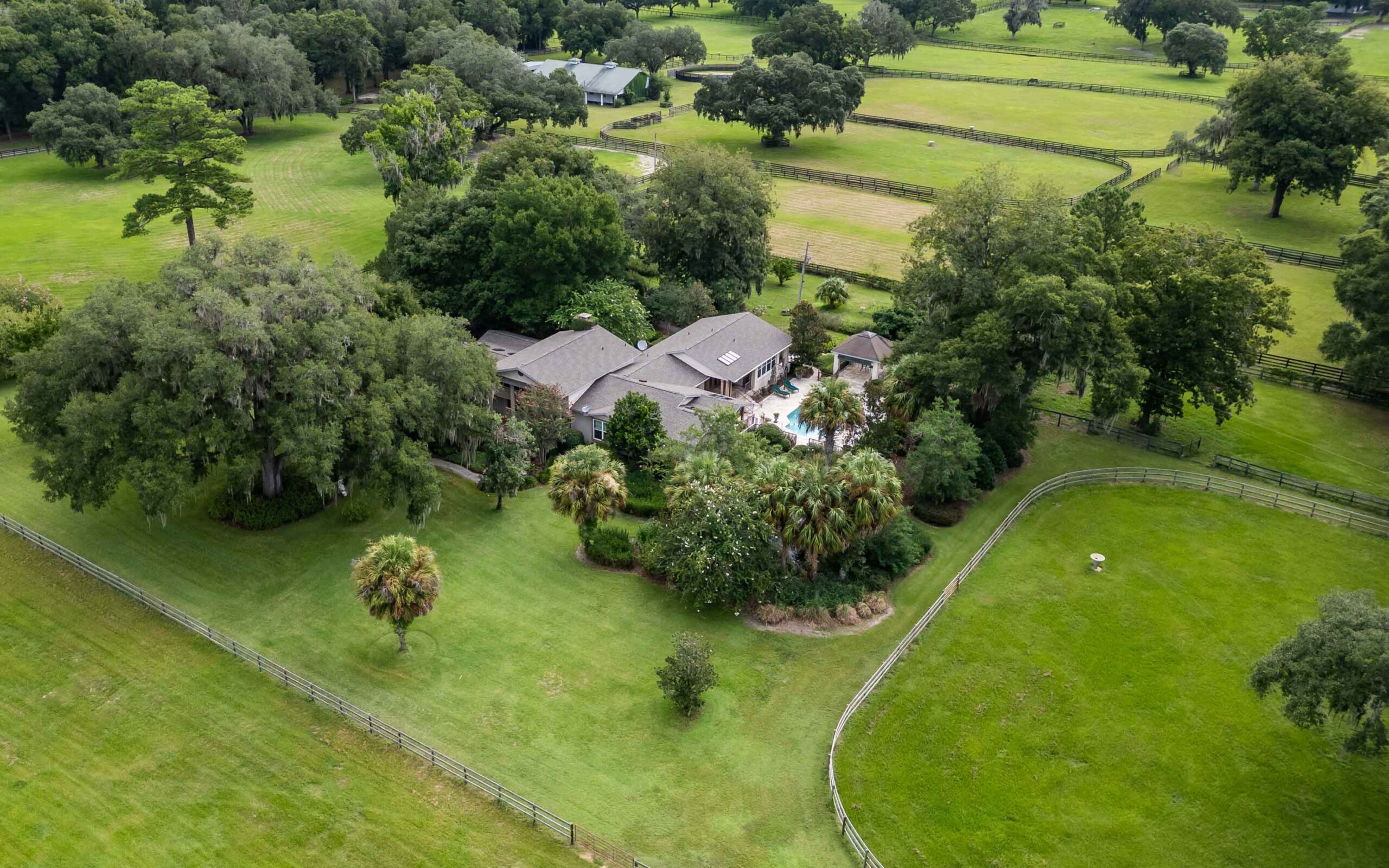 A luxurious pool area with plenty of room for seating, an attached hot tub and covered outdoor kitchen.