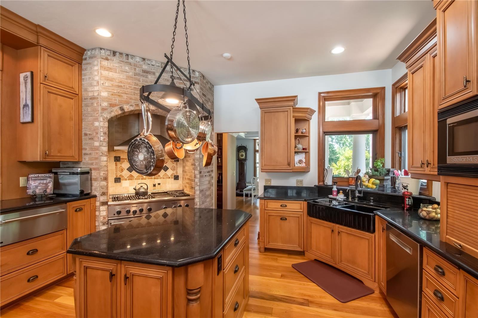 A gorgeous kitchen with oven alcove, custom cabinetry, and iron pot rack.