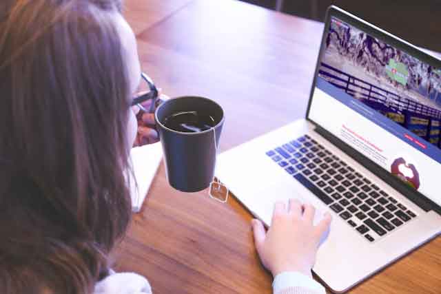 A woman enjoys a cup of tea and peruses the Give4Marion website.