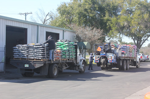 Workers load trucks with feed at OBS Quality Feeds